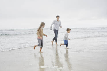 Father running on the beach with son and daughter - RORF03033