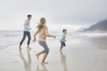 Father running on the beach with son and daughter - RORF03034