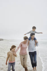 Parents walking with two children on the beach carrying son on the shoulders - RORF03039