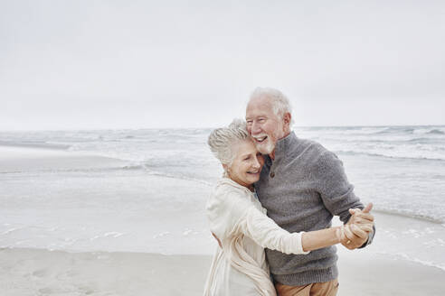 Happy senior couple dancing on the beach - RORF03043