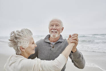 Happy senior couple dancing on the beach - RORF03045