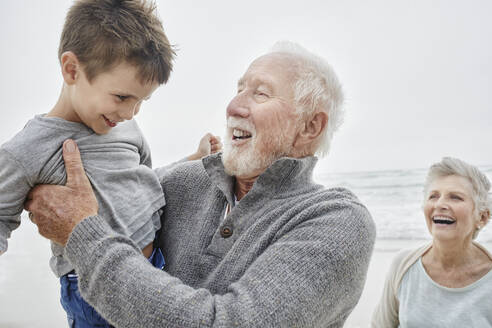 Happy grandparents spending quality time on the beach with grandson - RORF03051