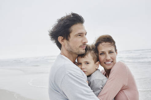 Besorgte Eltern umarmen ihren Sohn am windigen Strand - RORF03060