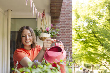 Mädchen bewässert Pfefferminzpflanzen auf dem Balkon - IHF01106