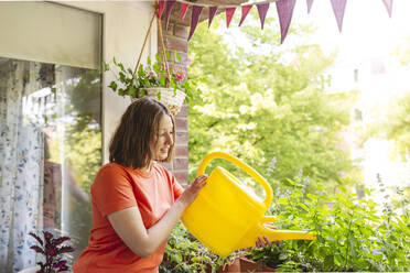 Teenager-Mädchen gießt Pflanzen auf dem Balkon - IHF01107