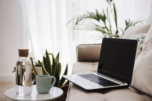 Laptop bei den Kissen auf der Couch zu Hause - EBBF05733