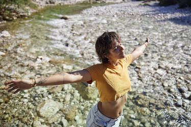Junge Frau mit geschlossenen Augen am Flussufer an einem sonnigen Tag - CVF02101