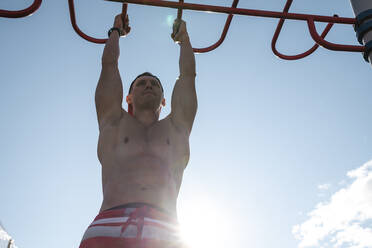 Man hanging on monkey bars at park - VPIF06917