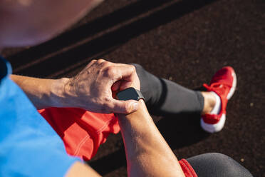 Man adjusting smart watch on sunny day - VPIF06922