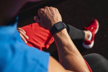 Sportler kontrolliert die Zeit auf seiner Smartwatch - VPIF06923