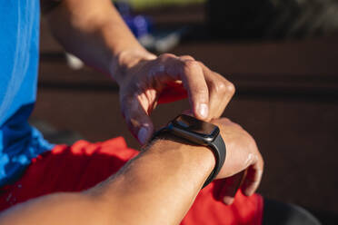 Hand of man adjusting smart watch on sunny day - VPIF06925