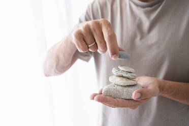 Mann stapelt Steine auf der Hand zu Hause - SVKF00438