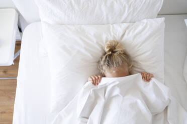Mädchen versteckt Gesicht mit Decke im Bett - SVKF00441