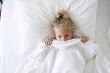 Girl peeking from blanket in bed - SVKF00442