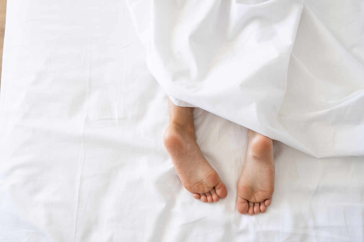 Girl lying in bed with bare feet stock photo