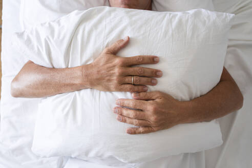 Mature man with pillow sleeping in bed - SVKF00469