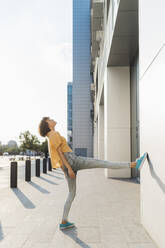 Woman standing on one leg near building - MEUF07619