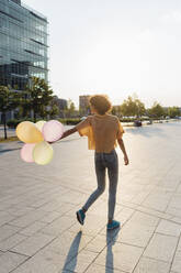 Frau spielt mit Luftballons bei Sonnenuntergang - MEUF07626