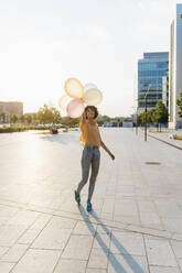 Junge Frau vergnügt sich mit Luftballons am Fußweg - MEUF07628