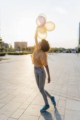 Junge Frau mit erhobener Hand, die Luftballons hält - MEUF07629