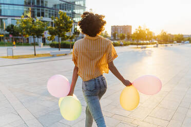 Frau mit Luftballons auf dem Fußweg - MEUF07639