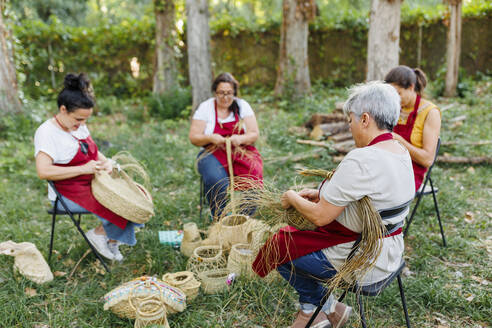 Kunsthandwerker mit Mitarbeitern beim Weben von Espartogras im Garten - MRRF02282