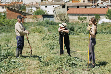 Farmers discussing at field on sunny day - MRRF02322