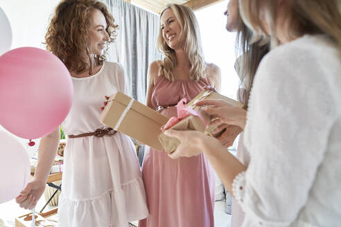 Smiling friends giving gift to pregnant woman - ABIF01812