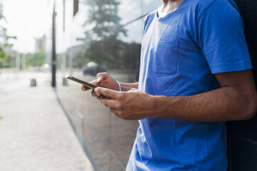 Man using smart phone leaning on wall - MEUF07674