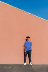 Young man standing in front of wall on sunny day - MEUF07686