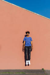 Young man levitating in front of coral wall - MEUF07689