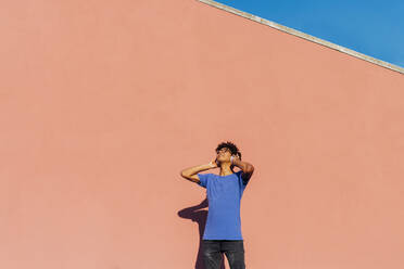 Young man listening music through wireless headphones on sunny day - MEUF07693
