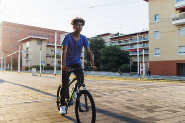 Junger Mann fährt Fahrrad in der Stadt - MEUF07733