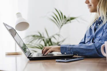 Businesswoman typing on laptop at home office - EBBF05761