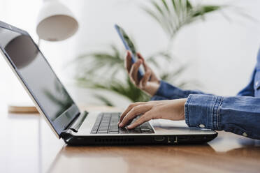 Freiberufler mit Laptop und Smartphone im Heimbüro - EBBF05762