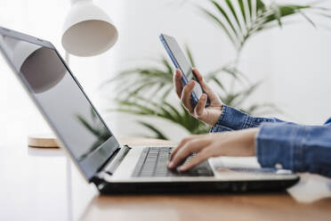 Hands of businesswoman using wireless technologies at home office - EBBF05763