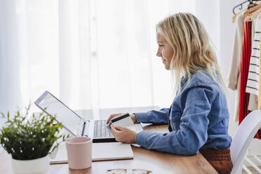 Junge Geschäftsfrau beim Online-Shopping mit Kreditkarte und Laptop im Home-Office - EBBF05789