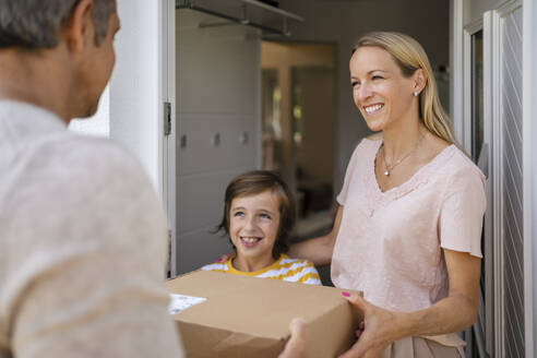 Happy woman with son receiving parcel at the front door - DIGF18601