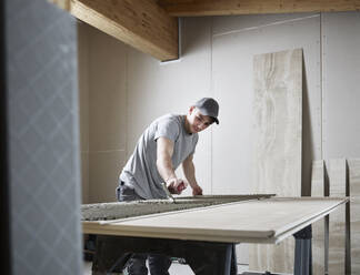 Tiler applying adhesive on tile at construction site - CVF02106