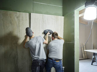 Fliesenleger beim Anbringen von Fliesen an der Wand mit Vakuumsauger auf der Baustelle - CVF02110
