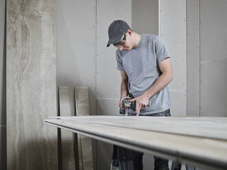 Tiler using drill on tile at construction site - CVF02112