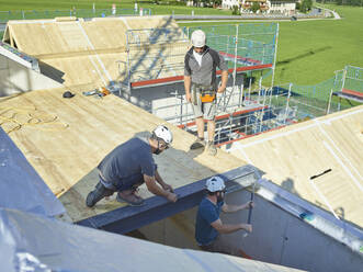 Zimmerleute mit Werkzeugen bei der Dachmontage auf der Baustelle - CVF02117