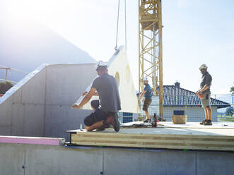 Bauarbeiter bei der Dachmontage an einem sonnigen Tag - CVF02124