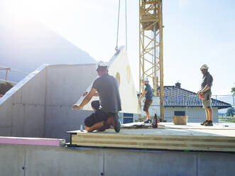 Construction workers installing roof on sunny day - CVF02124