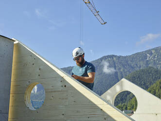 Handwerker mit Schutzhelm auf dem Dach einer Baustelle - CVF02127