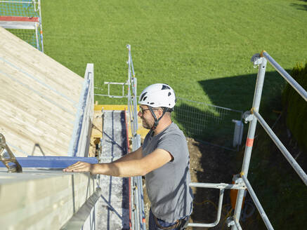Glücklicher Arbeiter mit Schutzhelm auf einer Baustelle - CVF02129