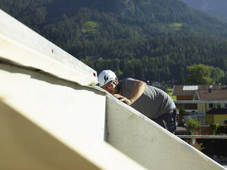Handwerker mit Schutzhelm bei der Arbeit auf einer Baustelle an einem sonnigen Tag - CVF02130