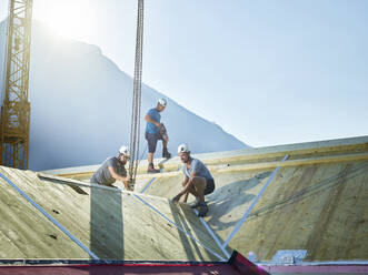 Zimmerleute arbeiten auf dem Dach mit einem Kran auf der Baustelle - CVF02146