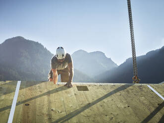 Carpenter working on roof in front of mountains - CVF02147