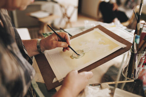 Ältere Künstlerin malt mit Pinsel zu Hause - MRRF02332